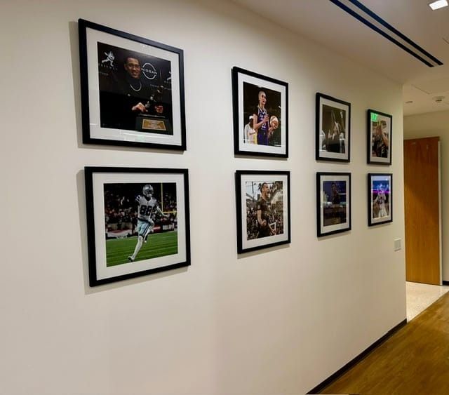 Photos in black frames hang on a white wall in a hallway.