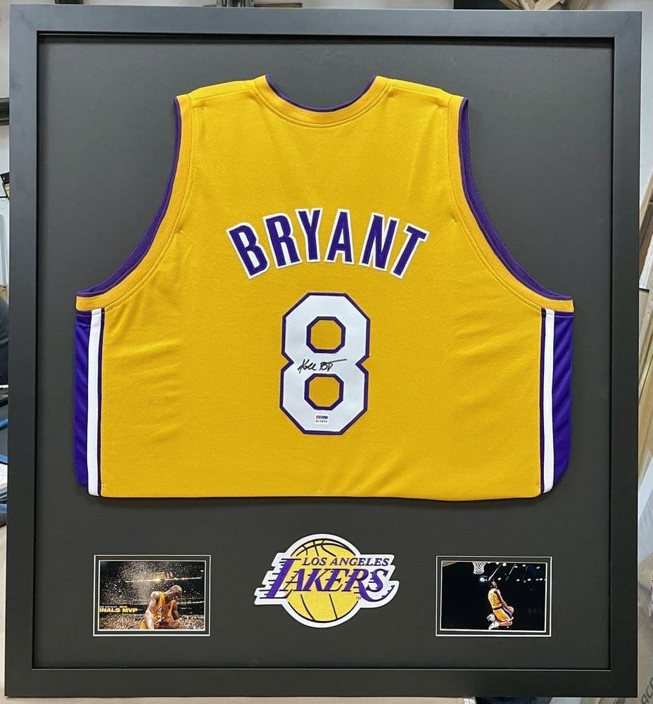 Framed Kobe Bryant Lakers jersey with signature, photos, and team logo, yellow/purple.