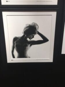 Silhouette of a person with arm raised, posed against a bright backdrop, in a framed monochrome artwork.