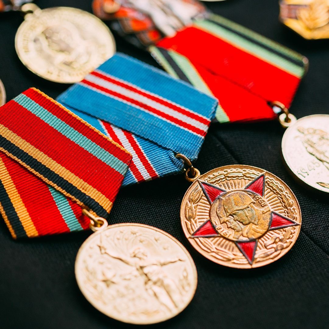 Close-up of several medals with colorful ribbons, likely awards, resting on a dark surface.