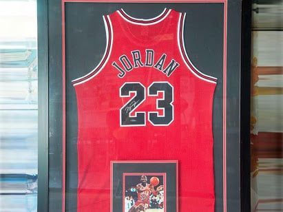 Framed Michael Jordan Chicago Bulls jersey with a photo below. Red, black, white colors.