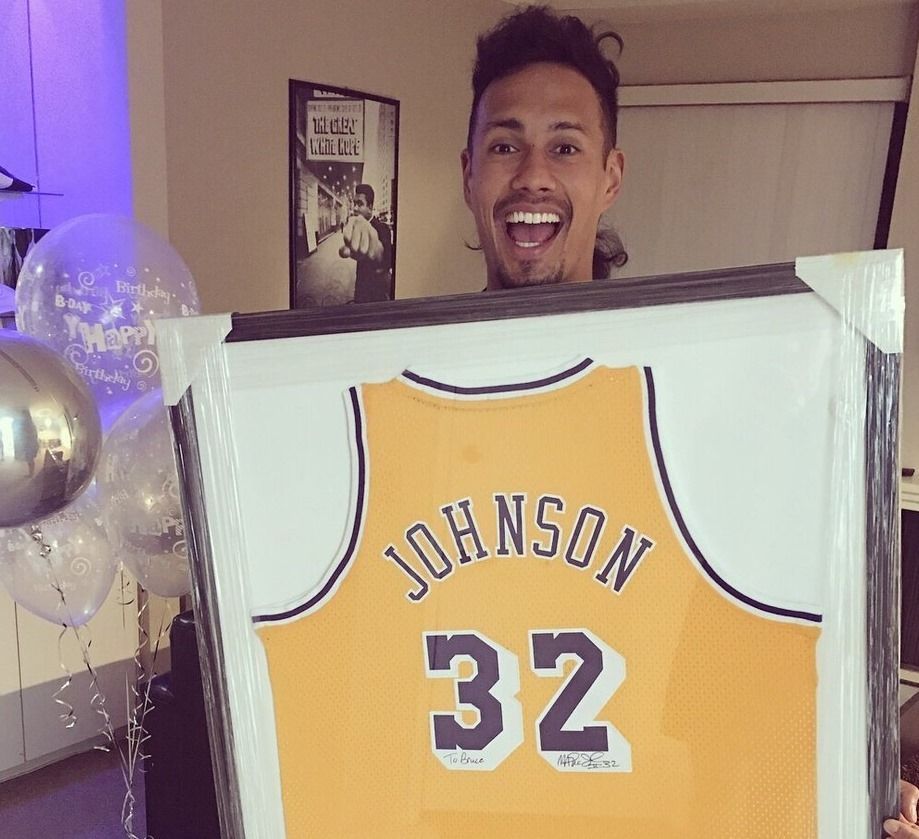 Man holding framed yellow Lakers jersey with 