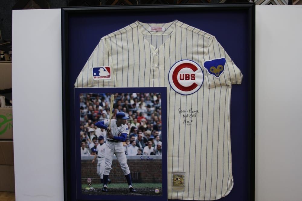 Framed Chicago Cubs jersey with photo of player. Cream pinstripe jersey with blue accents, signed. Photo of player batting.