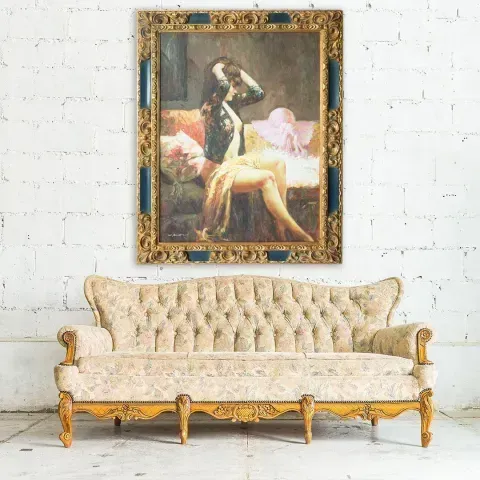 Antique sofa beneath a framed painting of a seated figure on a couch.