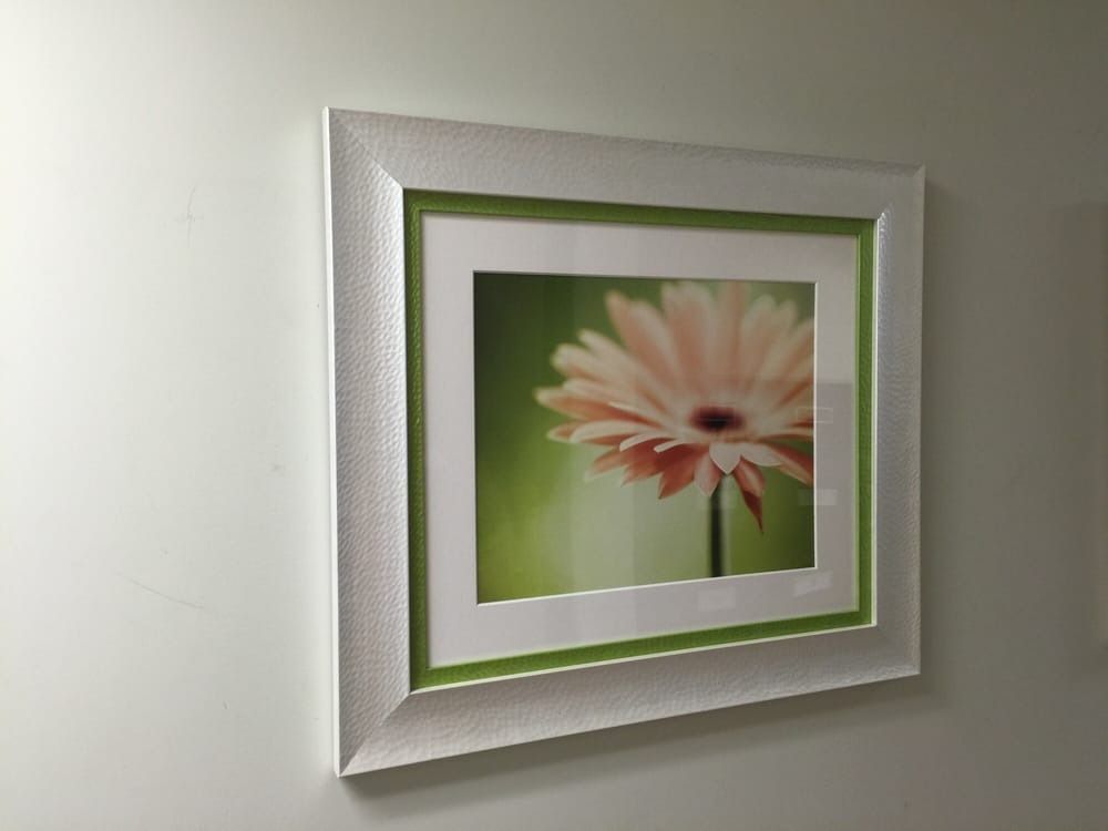 Framed photo of a peach gerbera daisy against a green background, with white and silver frame.