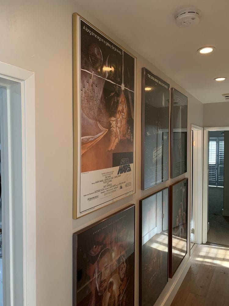 Wall in hallway with framed Star Wars movie posters.