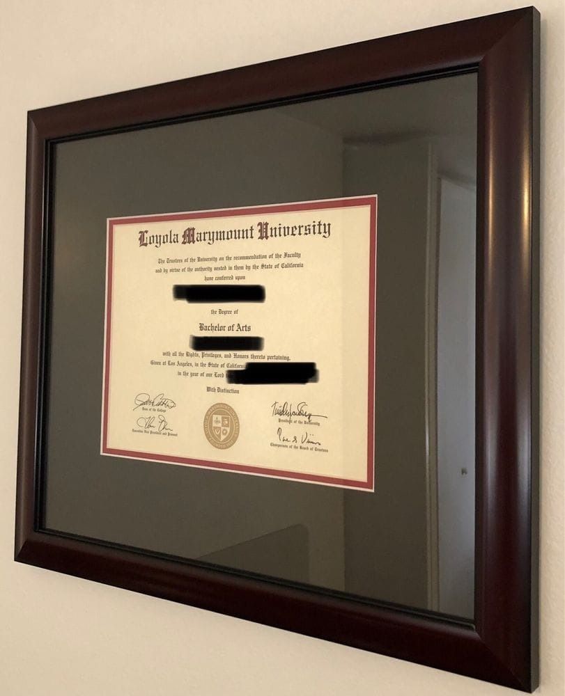 Framed Loyola Marymount University diploma, maroon frame, hung on a beige wall.