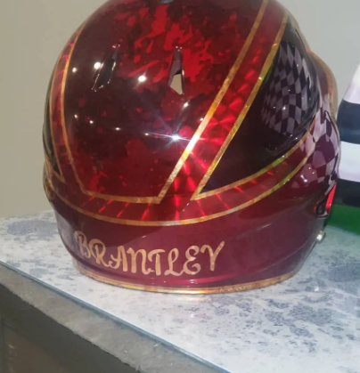 Red and black patterned sports helmet with gold trim and “BRANTLEY” written on the front.