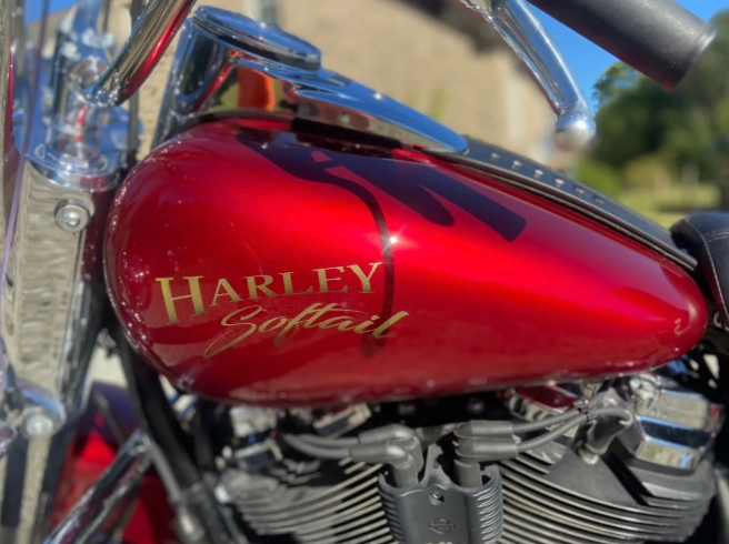 Red Harley-Davidson Softail fuel tank with chrome engine in sunlight