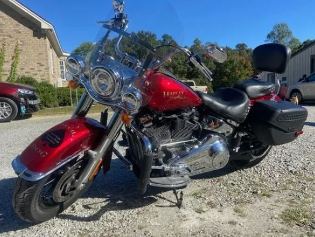 Red touring motorcycle parked on gravel in front of a stone building under a blue sky.