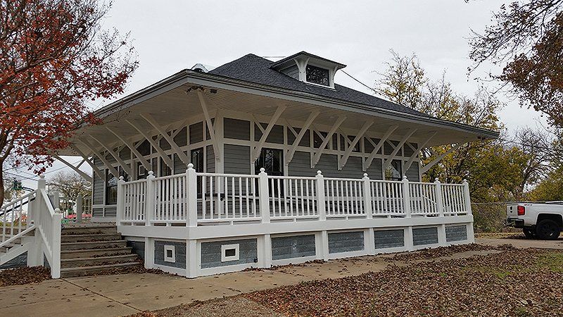 A white house with a porch and a truck parked in front of it