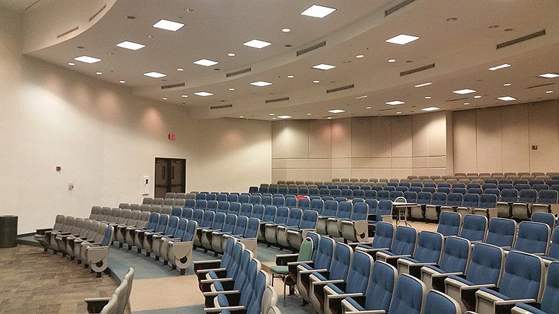 A large auditorium filled with rows of blue chairs