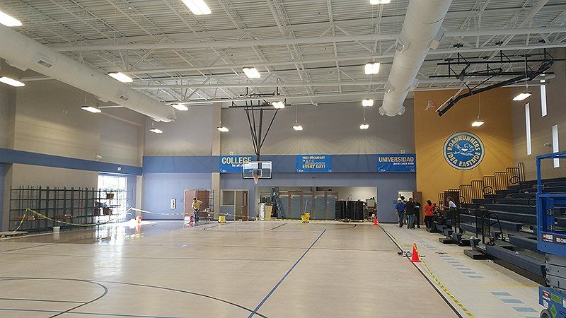 A large indoor gym with a basketball hoop and bleachers
