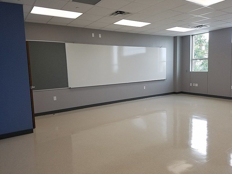 An empty classroom with a whiteboard and a blackboard