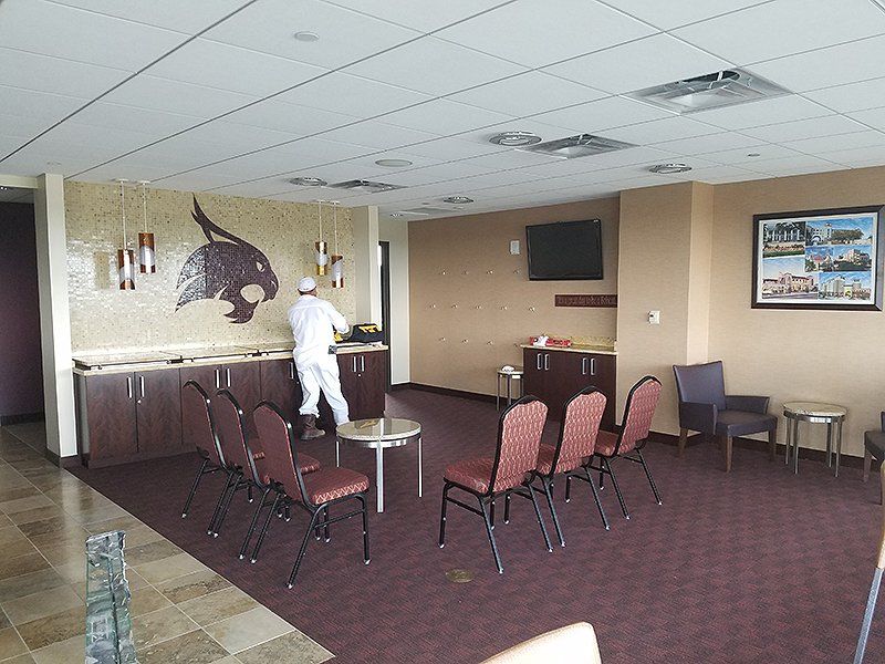 A man is standing in a room with chairs and tables