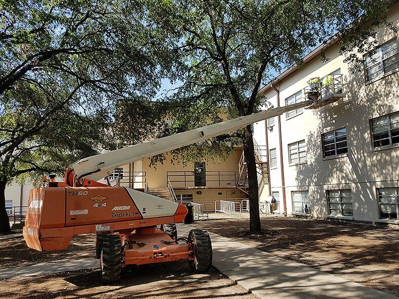 A large orange and white lift is parked in front of a building
