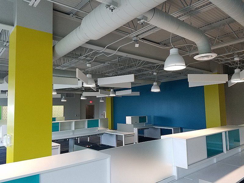 An empty office with blue and yellow walls and white cubicles