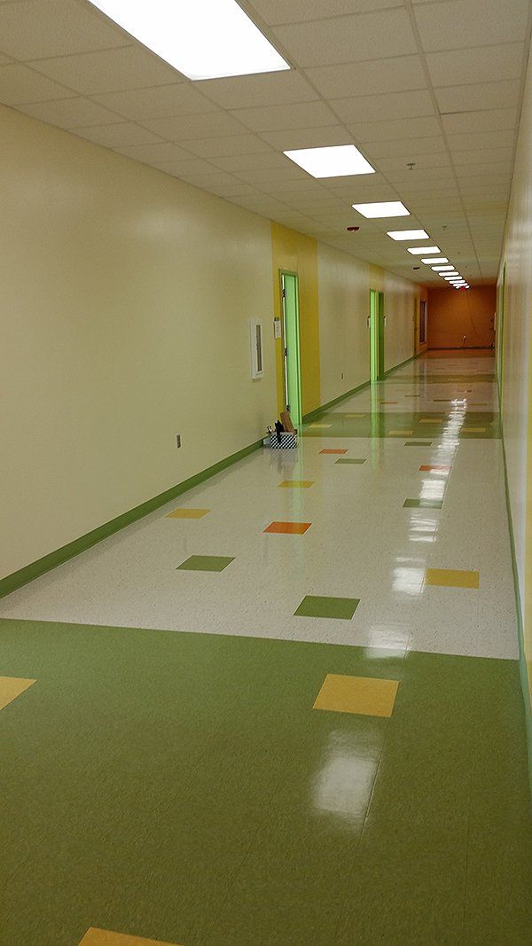 A long hallway with green and yellow tile floors and white walls