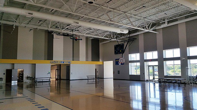 An empty gym with a basketball hoop