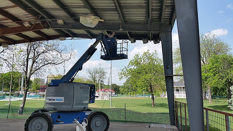 A blue lift is sitting under a roof of a building