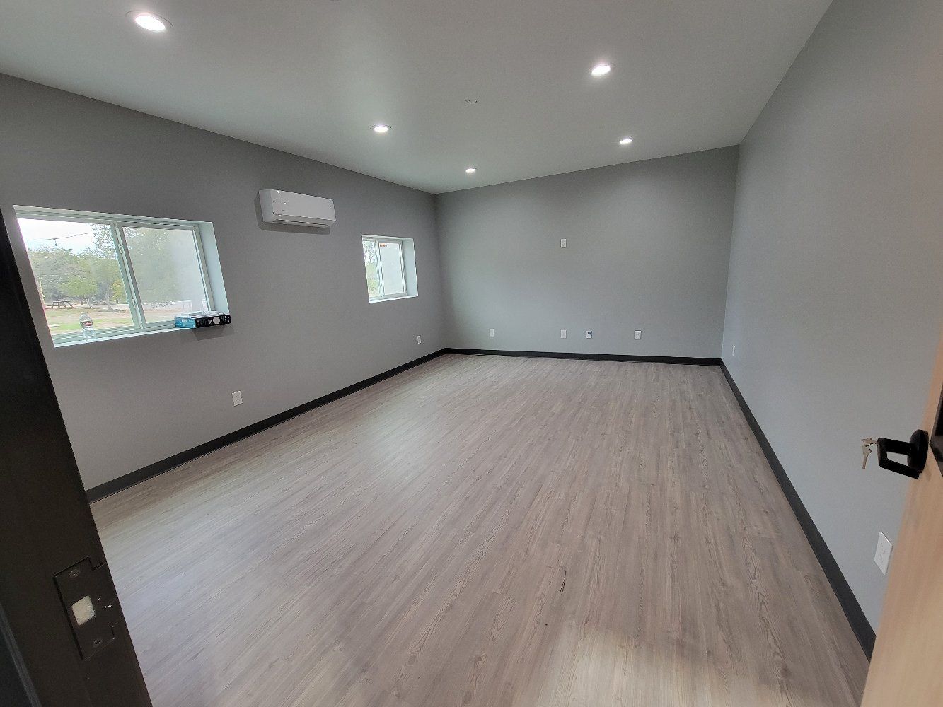 A large empty room with hardwood floors and gray walls