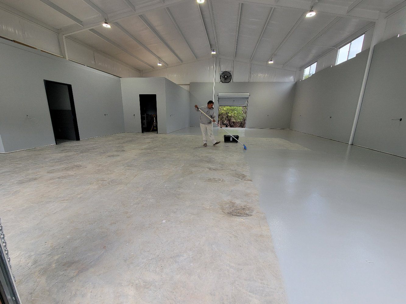 A man is standing in a large empty warehouse