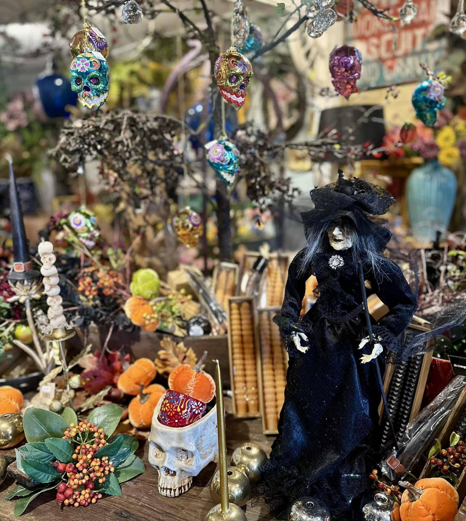 Halloween display with witch figure, skull ornaments, pumpkins, and fall foliage.