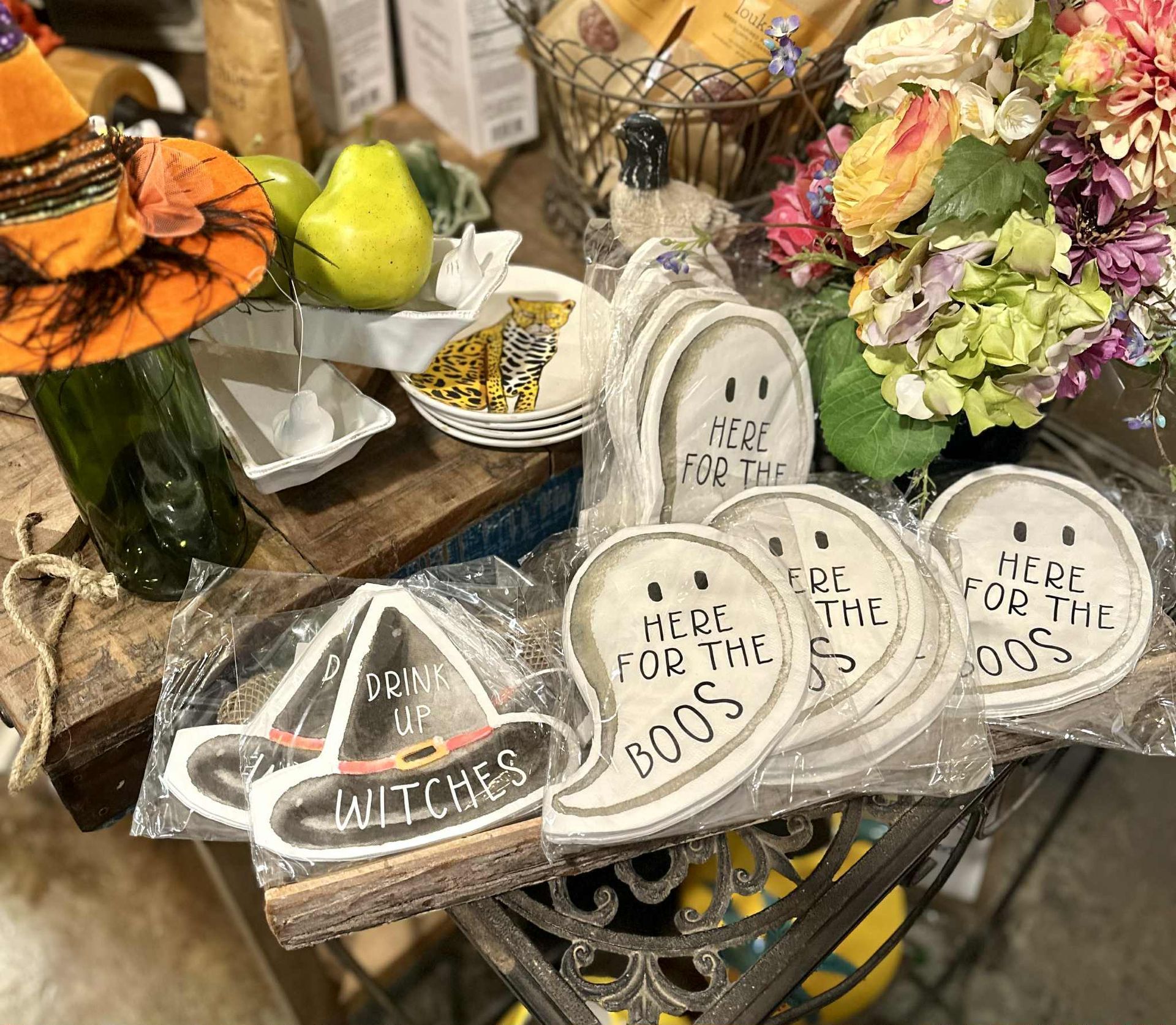 Halloween decorations: ghost and witch hat signs, flowers, pears, and wine bottle with a witch hat.