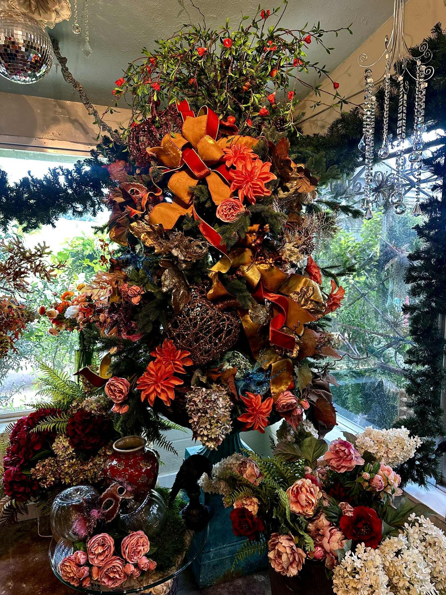 A tall, colorful floral arrangement with red, orange, and gold accents on a table.