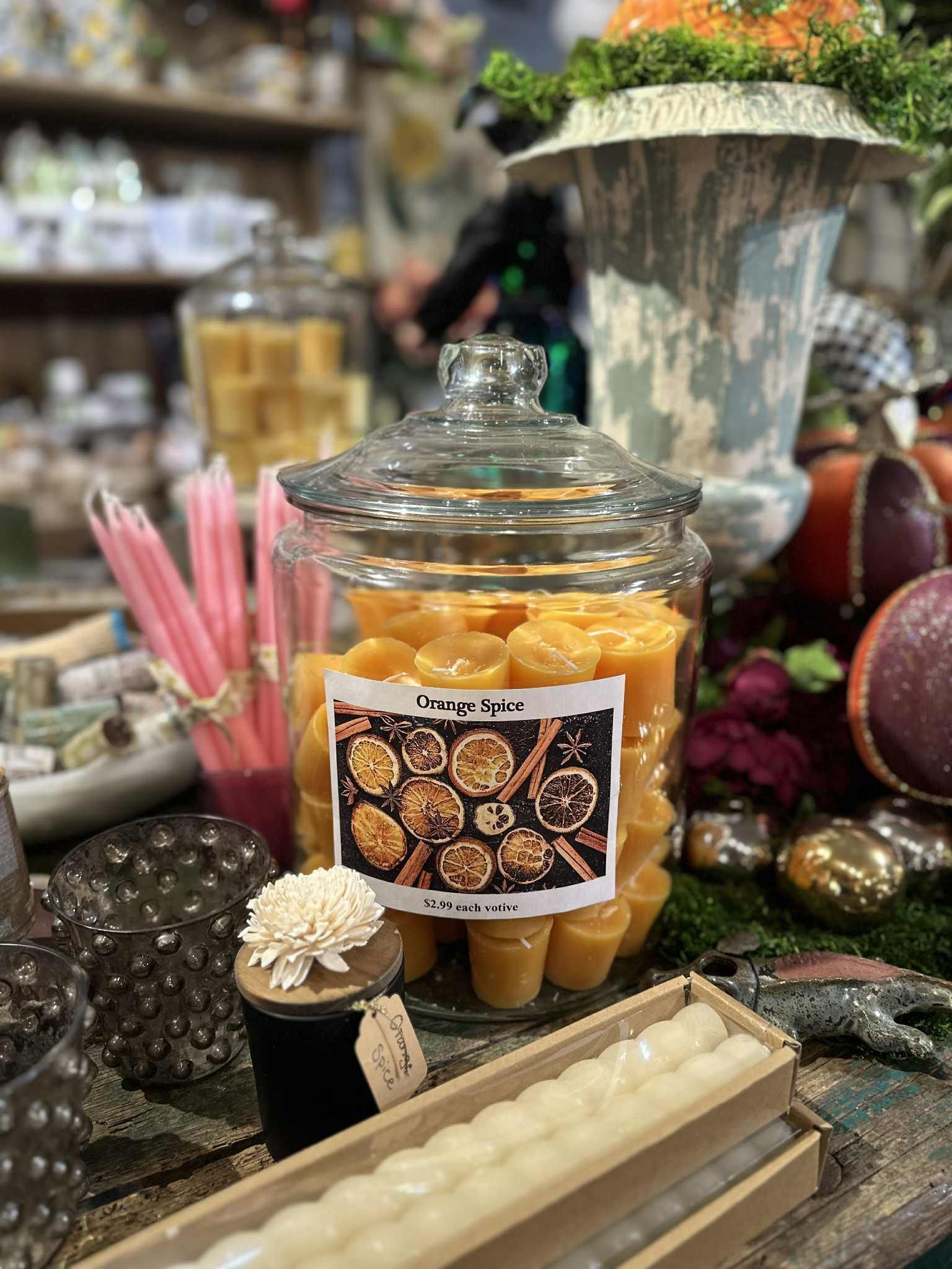 Glass jar filled with orange spice wax melts; a cozy display of candles and decor.
