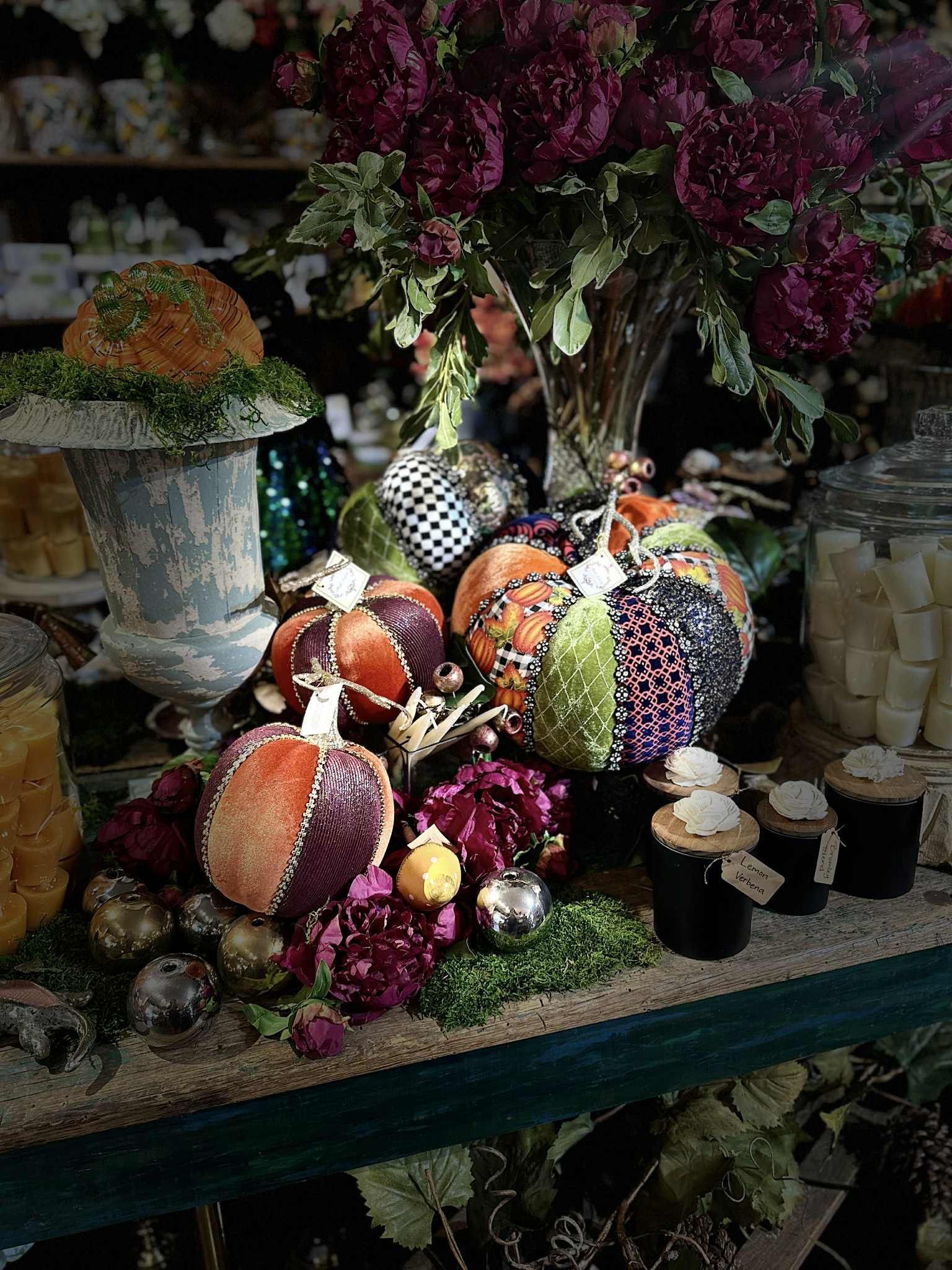 Display of colorful fabric pumpkins, flowers, and decorative items on a shelf.