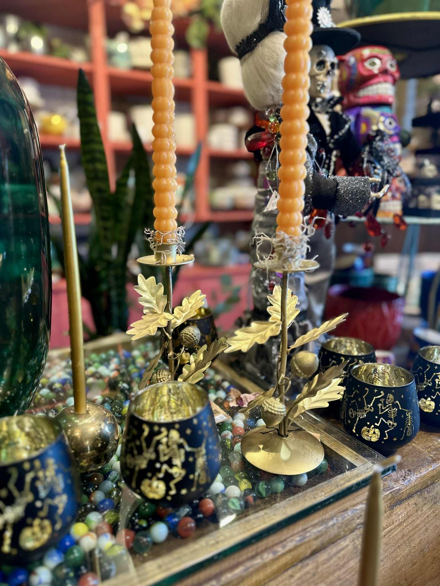 Candle holders with orange candles, gold accents, and Halloween decorations.
