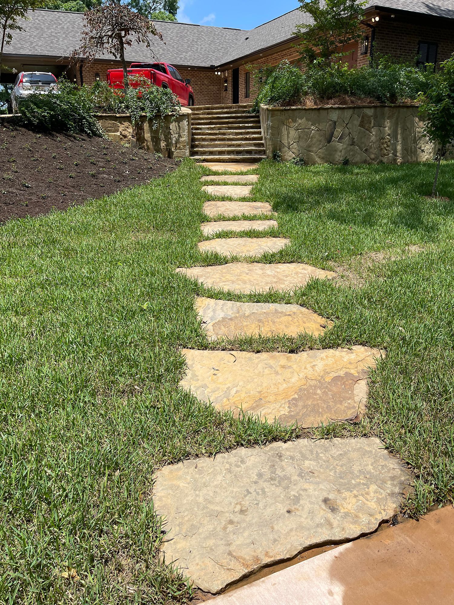 A stone walkway leading to a house with stairs.