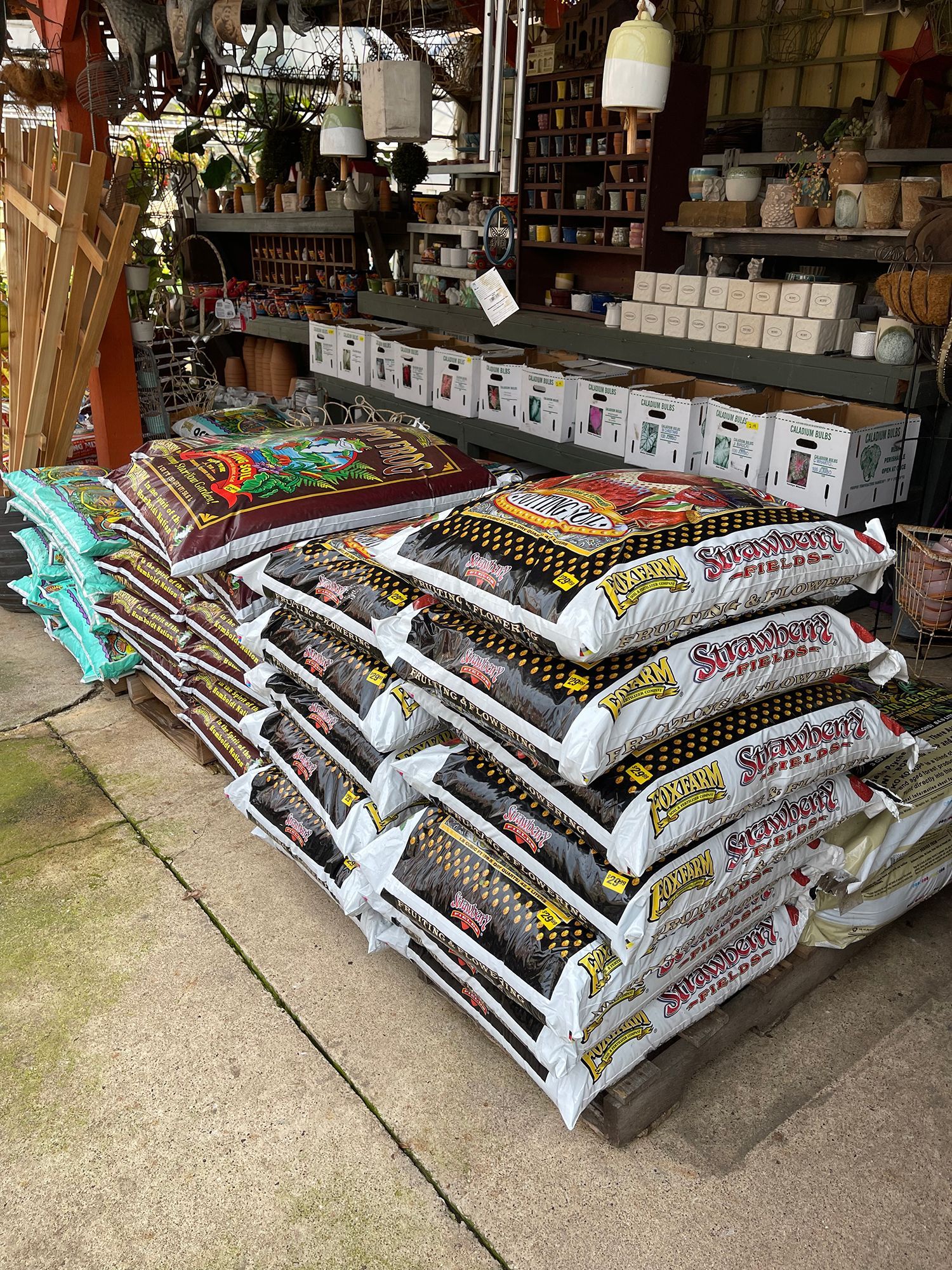 A bunch of bags of soil are stacked on top of each other in a store.