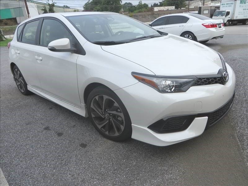 A white toyota auris is parked in a parking lot.