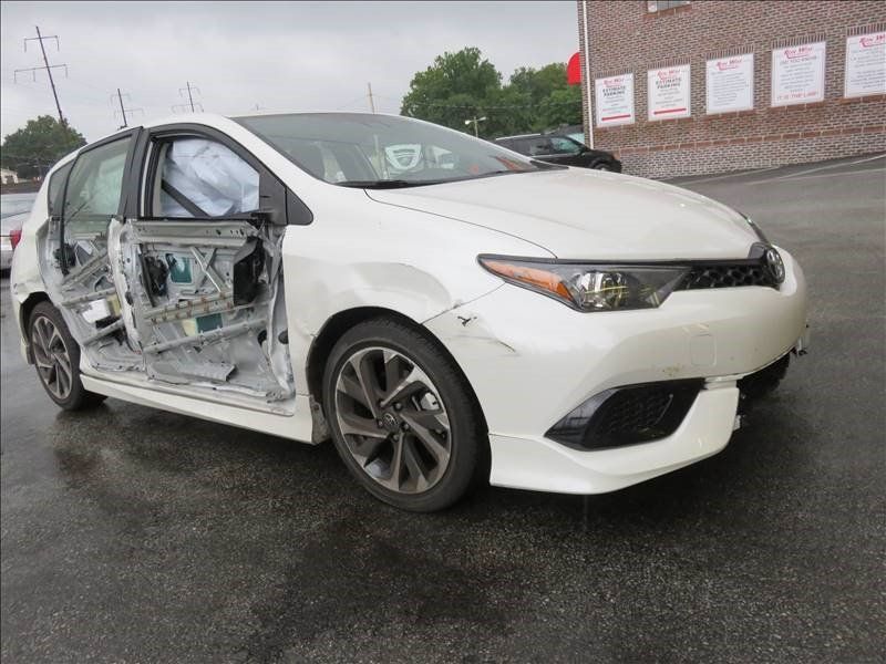 A white car with its doors open is parked in a parking lot.
