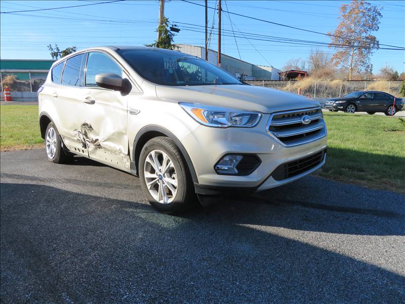 A white ford escape with a damaged side is parked on the side of the road.