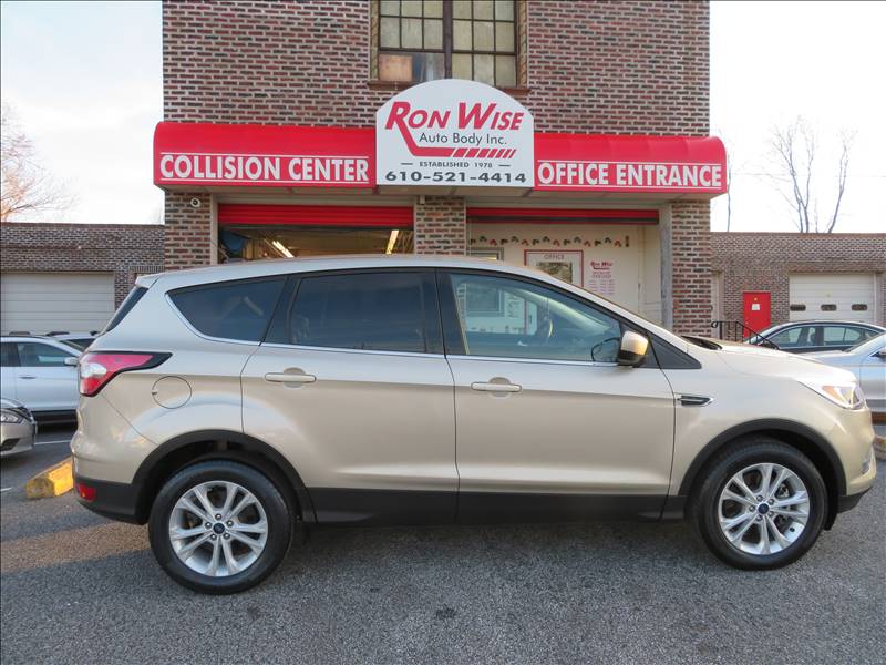 A ford escape is parked in front of a ron wise collision center