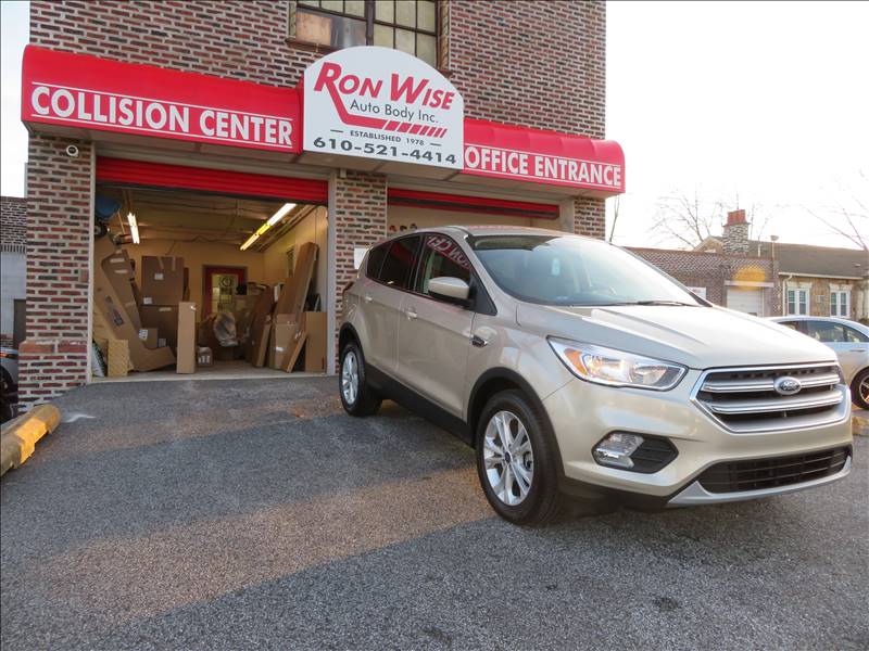 A ford escape is parked in front of a collision center