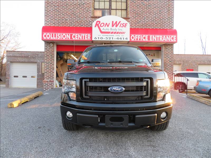 A ford truck is parked in front of a ron wise collision center