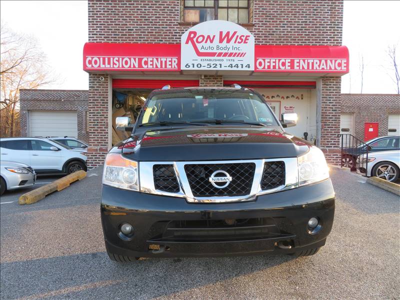 A nissan is parked in front of a ron wise collision center