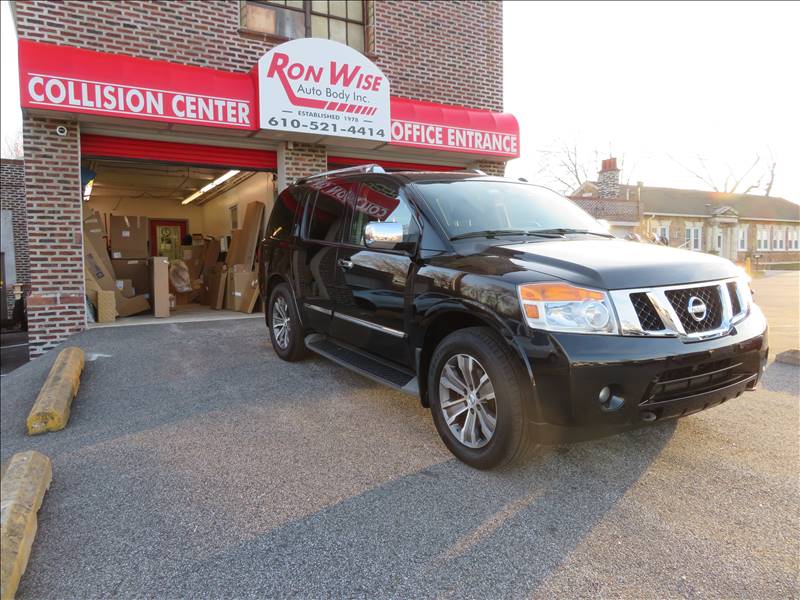 A black suv is parked in front of a collision center