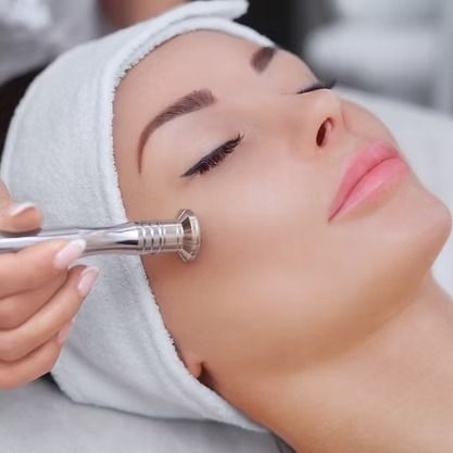 Woman receiving a facial treatment with a handheld skincare device on her cheek