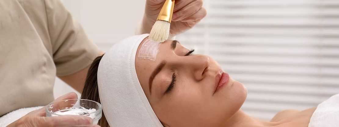Spa facial treatment with a brush applying product to a reclining client’s forehead