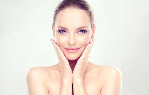 Smiling woman with hands on her cheeks against a bright white background