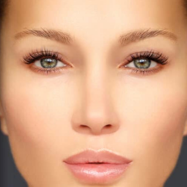 Close-up of a woman’s face with green eyes, soft makeup, and a neutral expression