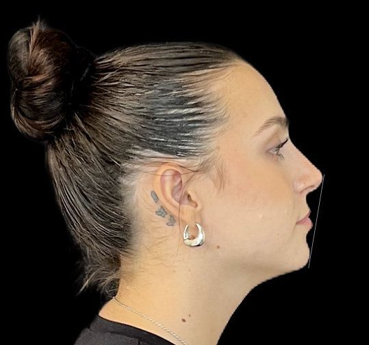 Profile view of a person with a sleek bun and silver hoop earrings against a black background