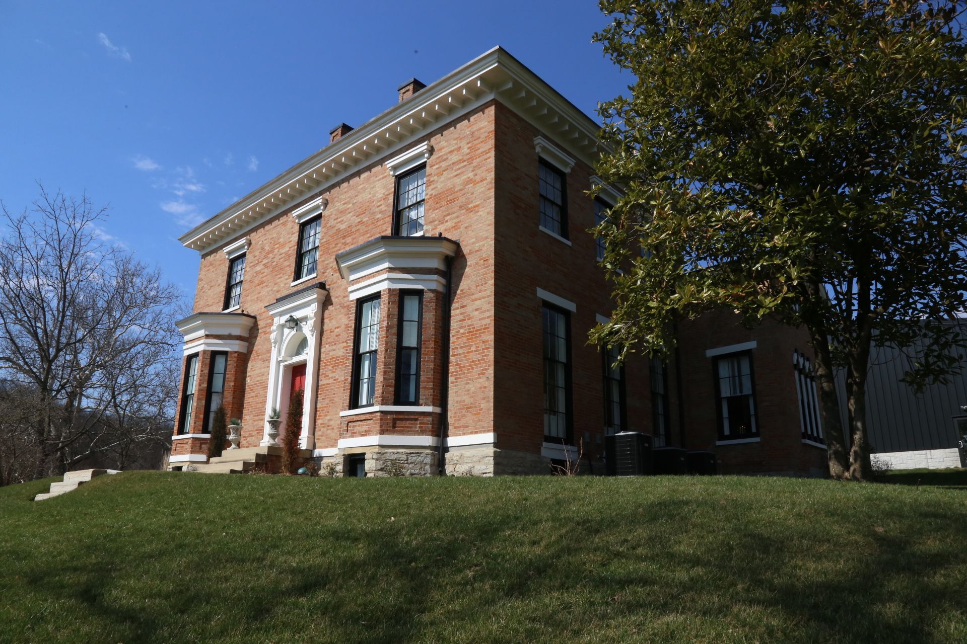 a large brick house sits on top of a grassy hill