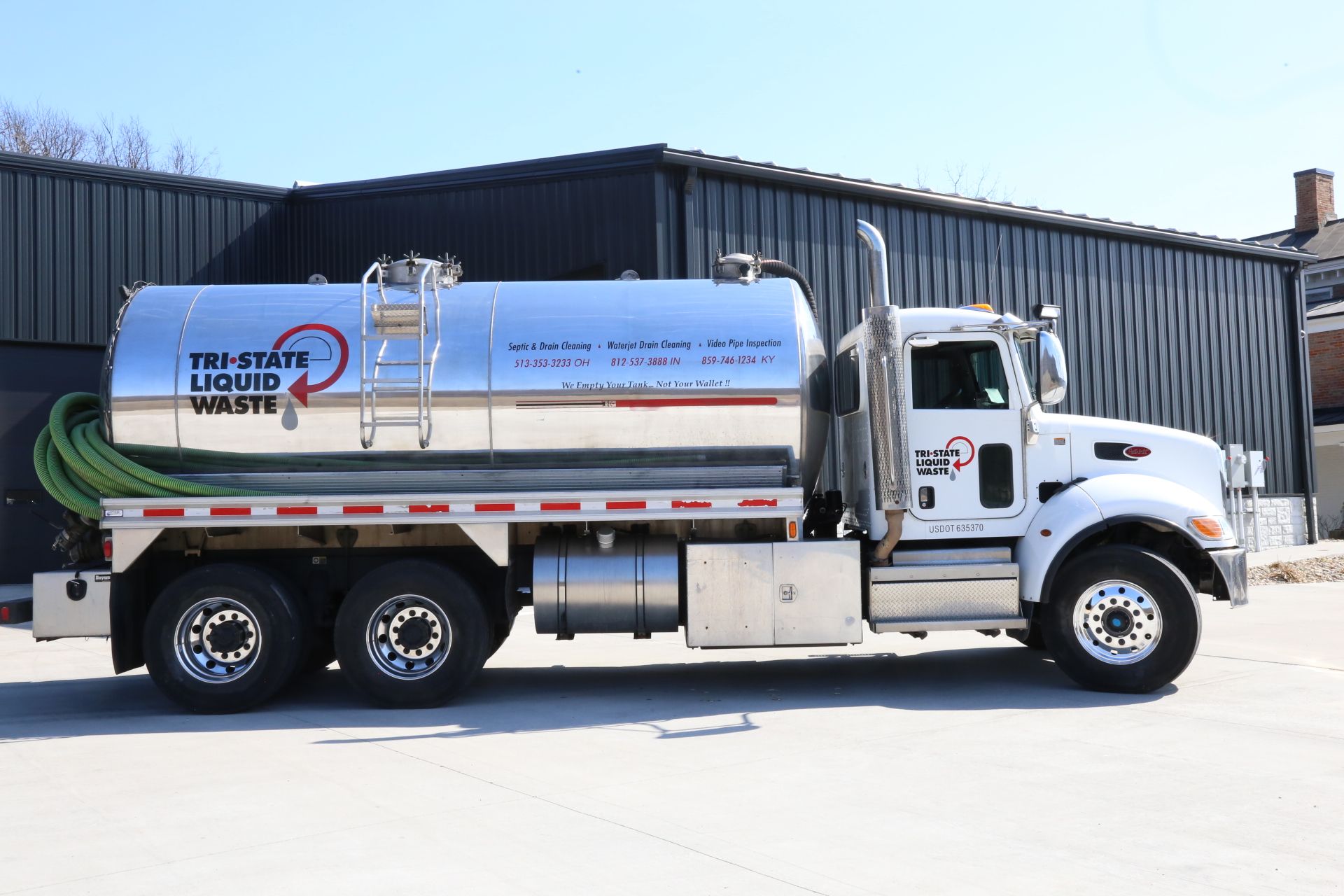 a stainless steel liquid waste truck is parked in front of a building .