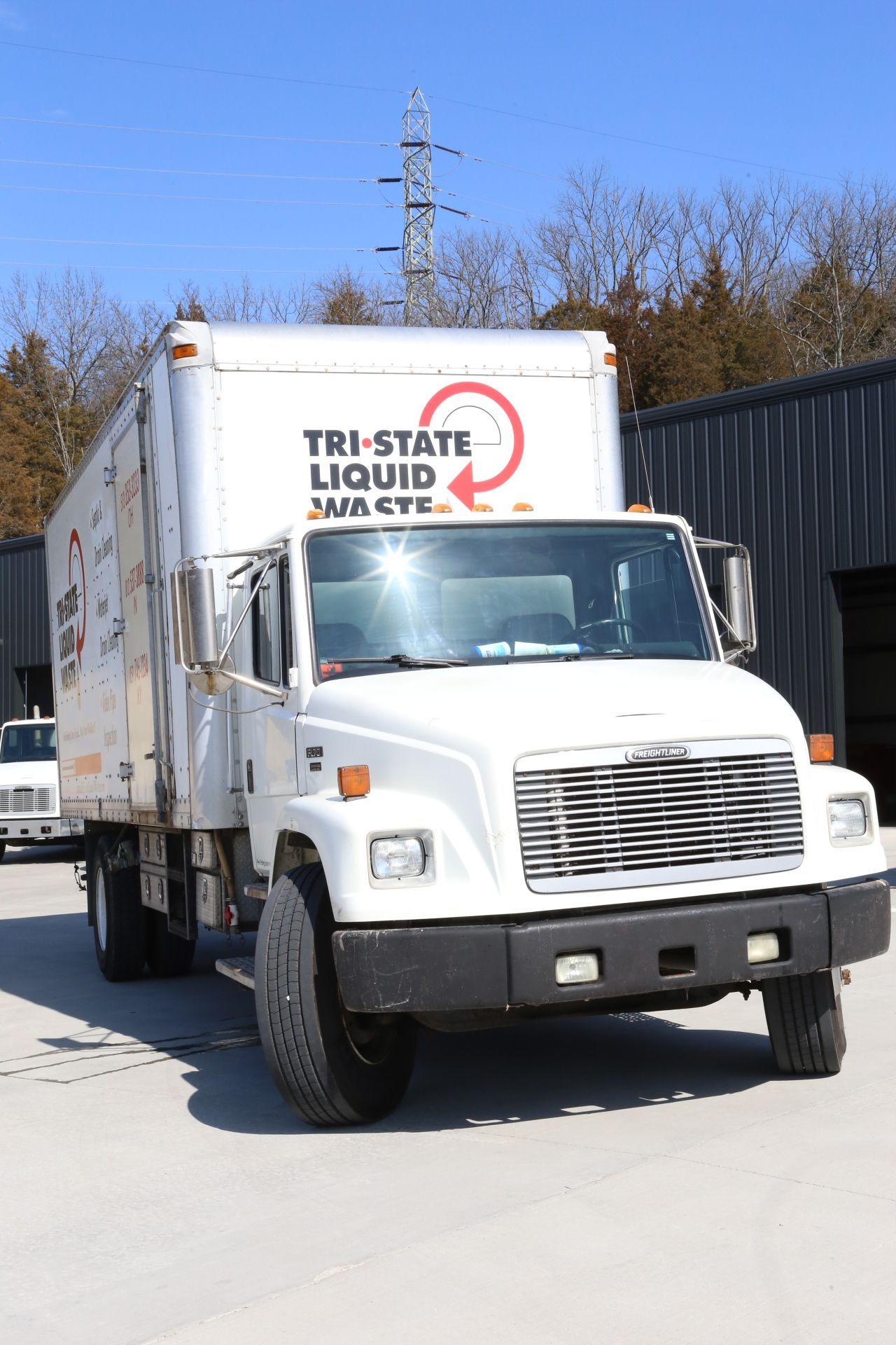 a white tri-state liquid waste truck is parked in front of a building .